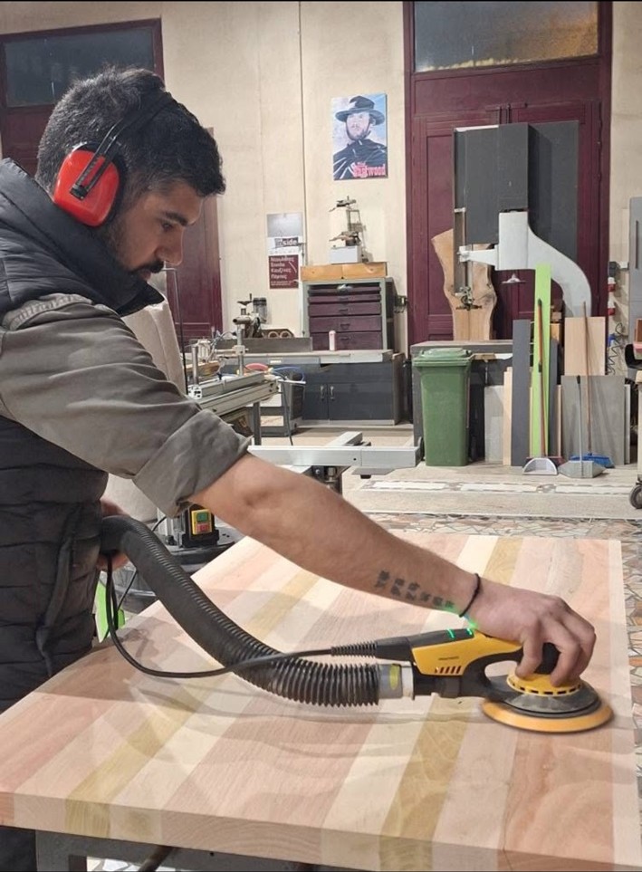 Panagiotis Simatos working on a solid wood furniture piece in the workshop
